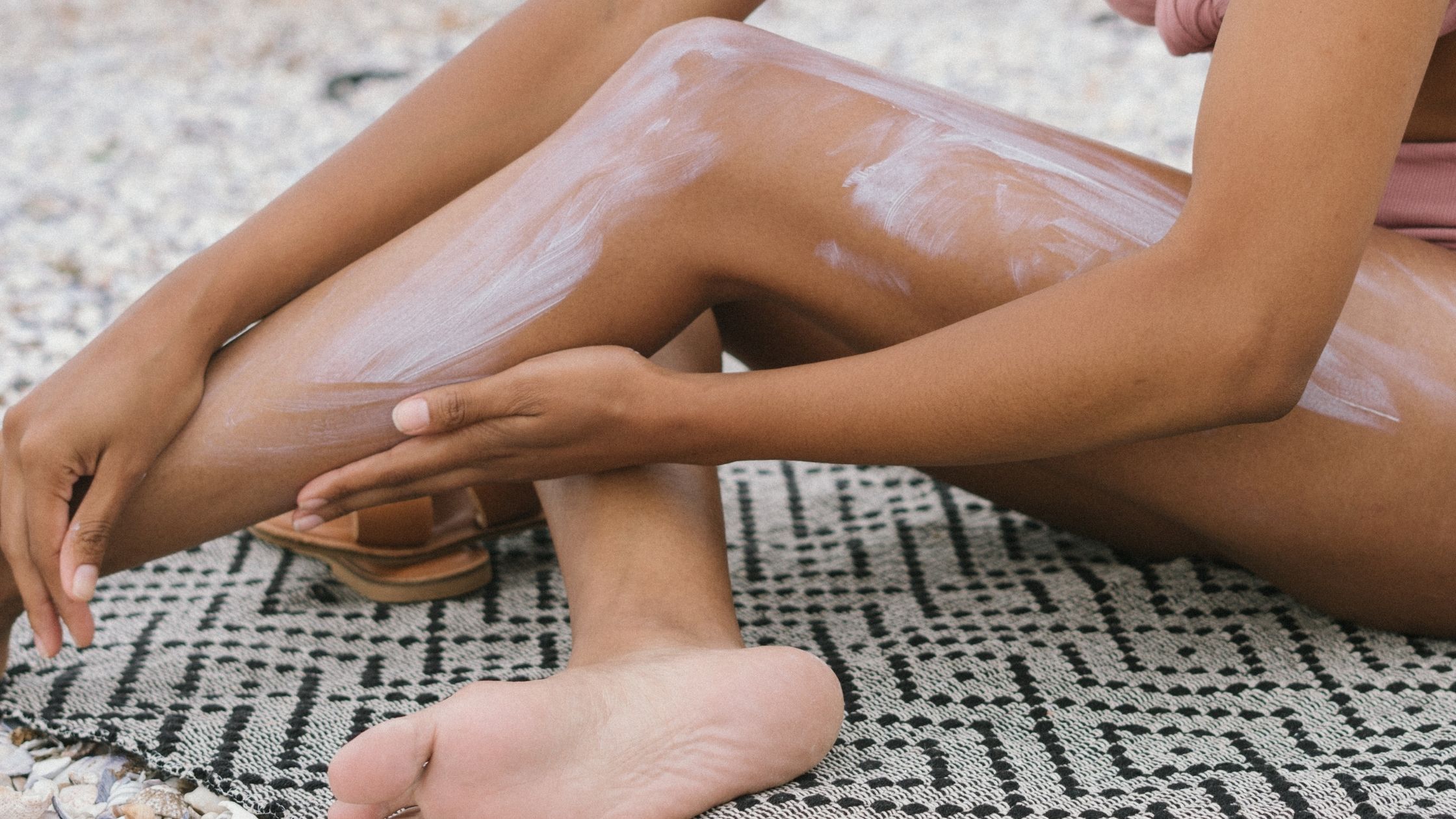 Woman applying sunscreen on beach towel